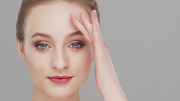 Retrato de estudio de mujer joven, hermosa y natural sobre fondo gris. Levantamiento facial, cosméticos y maquillaje. — Vídeo de stock