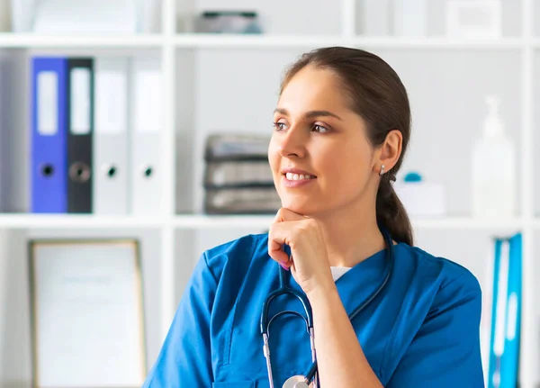 Berufsärztin im Krankenhausbüro, Porträt einer jungen und attraktiven Ärztin mit Schutzmaske. — Stockfoto