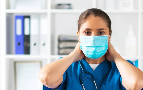 Médico profissional que trabalha no escritório do hospital, retrato do médico fêmea novo e atrativo na máscara protetora. — Fotografia de Stock