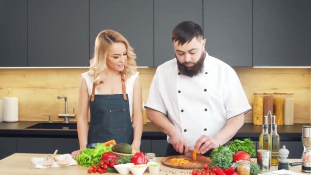 Młoda kobieta i mężczyzna przygotować jedzenie i gospodarzem programu kulinarnego. Blogerzy płyną z kuchni. Zdrowe przygotowanie żywności. — Wideo stockowe