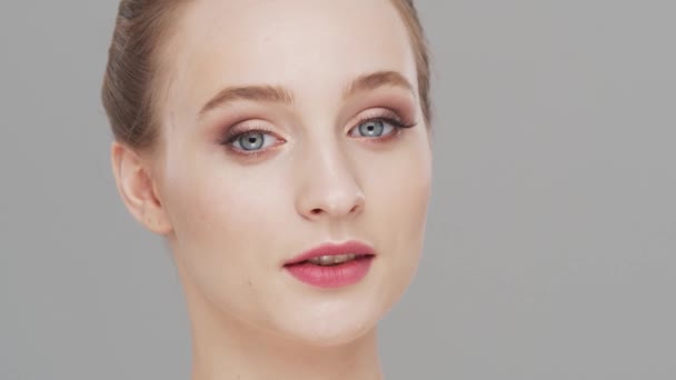 Retrato de estudio de mujer joven, hermosa y natural sobre fondo gris. Levantamiento facial, cosméticos y maquillaje. — Vídeo de stock