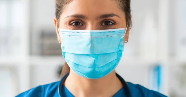 Berufsärztin im Krankenhausbüro, Porträt einer jungen und attraktiven Ärztin mit Schutzmaske. — Stockfoto