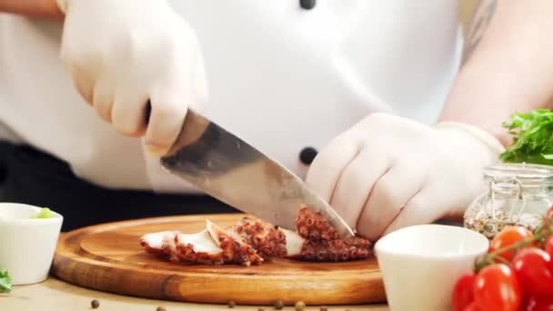 O jovem chef está cortando polvo em uma cozinha moderna. O homem prepara comida em casa. Cozinhar alimentos saudáveis. — Vídeo de Stock