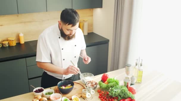 Young prepara un poke bowl en una cocina moderna. El hombre prepara comida en casa. Cocinar alimentos saludables. — Vídeo de stock