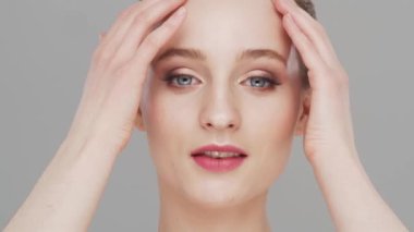 Gri arka planda genç, güzel ve doğal bir kadının stüdyo portresi. Yüz gerdirme, makyaj ve makyaj malzemeleri..