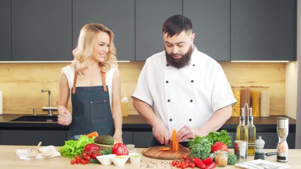 Young woman and man prepare food and host a cooking show. The bloggers stream from kitchen. Healthy food preparation. — Stock Video