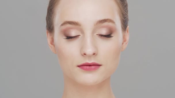 Retrato de estudio de mujer joven, hermosa y natural sobre fondo gris. Levantamiento facial, cosméticos y maquillaje. — Vídeos de Stock