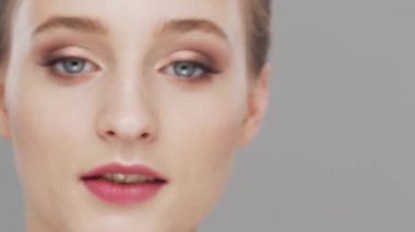 Gri arka planda genç, güzel ve doğal bir kadının stüdyo portresi. Yüz gerdirme, makyaj ve makyaj malzemeleri..