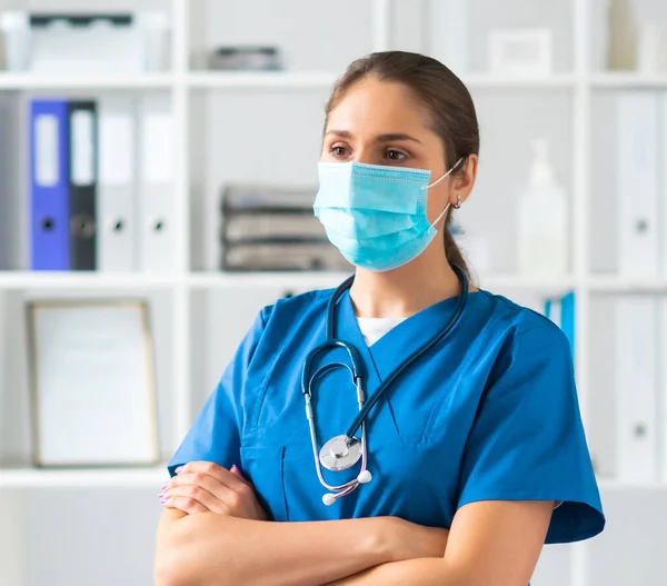 Professionele arts werkzaam in het ziekenhuis kantoor, Portret van jonge en aantrekkelijke vrouwelijke arts met beschermend masker. — Stockfoto