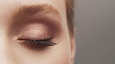 Gri arka planda genç, güzel ve doğal bir kadının stüdyo portresi. Yüz gerdirme, makyaj ve makyaj malzemeleri..