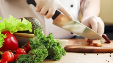 Genç aşçı modern bir mutfakta ahtapot kesiyor. Adam evde yemek hazırlıyor. Sağlıklı yemek pişirmek..