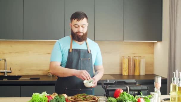 Joven chef que prepara carne a la parrilla en una cocina moderna. El hombre prepara comida en casa. Cocinar alimentos saludables. — Vídeos de Stock