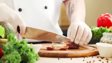 Genç aşçı modern bir mutfakta ahtapot kesiyor. Adam evde yemek hazırlıyor. Sağlıklı yemek pişirmek..