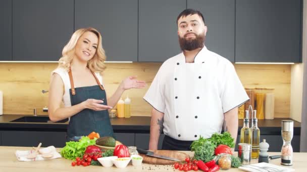 Mujer joven y hombre preparan comida y organizan un programa de cocina. Los bloggers fluyen desde la cocina. Preparación de alimentos saludables. — Vídeos de Stock
