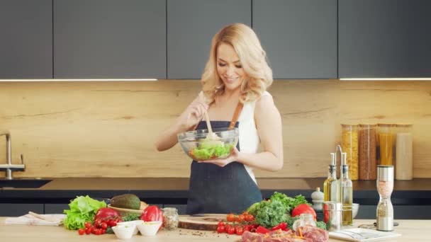 Mujer joven prepara la comida y organiza un espectáculo de cocina. El blogger fluye desde la cocina. Preparación vegetariana de alimentos saludables. — Vídeos de Stock