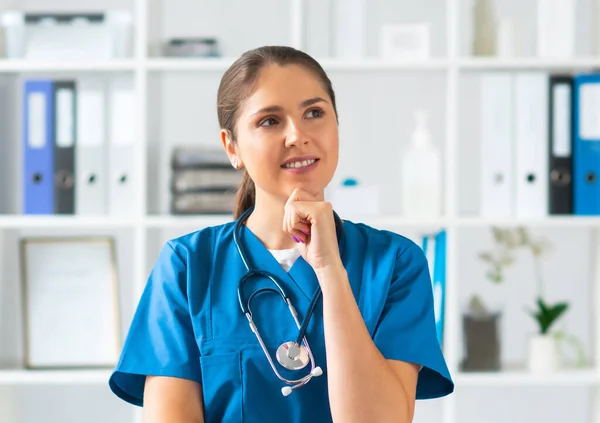 Berufsärztin im Krankenhausbüro, Porträt einer jungen und attraktiven Ärztin mit Schutzmaske. — Stockfoto