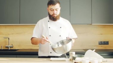 Young modern bir mutfakta kremalı tatlı hazırlıyor. Adam evde yemek hazırlıyor. Sağlıklı yemek pişirmek..
