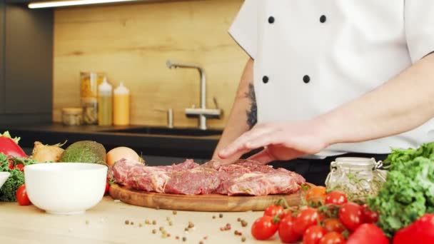 Młody kucharz kroi mięso w nowoczesnej kuchni. Facet przygotowuje jedzenie w domu. Gotowanie zdrowej żywności. — Wideo stockowe