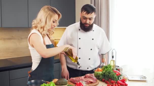 Mladá žena a muž připravit jídlo a hostit kuchařskou show. Bloggeři proudí z kuchyně. Zdravá výživa. — Stock video