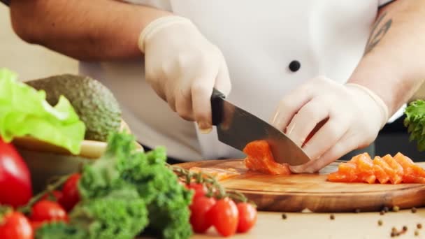 O jovem chef está cortando cenouras em uma cozinha moderna. O homem prepara comida em casa. Cozinhar alimentos saudáveis. — Vídeo de Stock