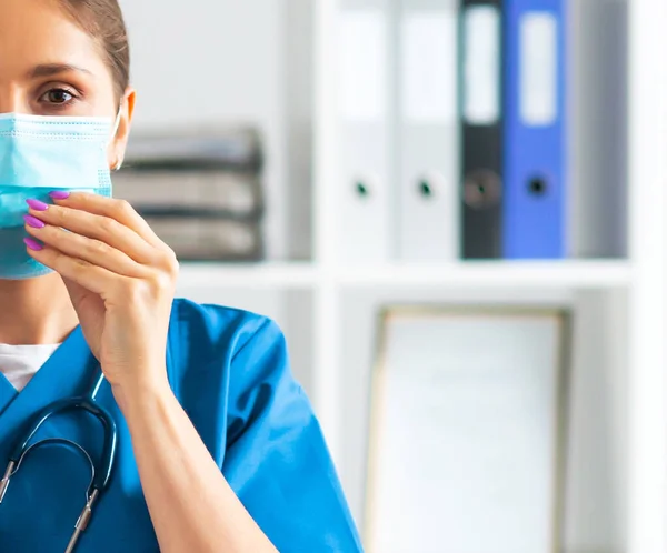 Professionell läkare som arbetar på sjukhus kontor, Porträtt av ung och attraktiv kvinnlig läkare i skyddsmask. — Stockfoto