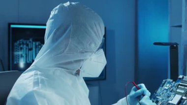 Mikro elektronik mühendisi, bilgisayar sistemleri ve mikroişlemciler üzerine modern bir bilim laboratuvarında çalışıyor. Elektronik fabrika işçisi ana kartı test ediyor ve yazılımı kodluyor..