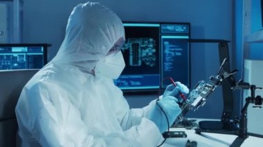 Mikro elektronik mühendisi, bilgisayar sistemleri ve mikroişlemciler üzerine modern bir bilim laboratuvarında çalışıyor. Elektronik fabrika işçisi ana kartı test ediyor ve yazılımı kodluyor..