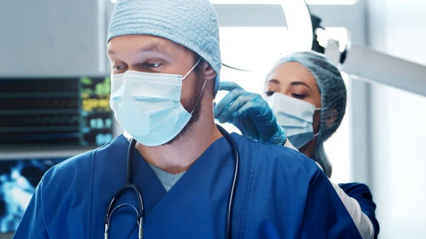 Médecins professionnels travaillant en médecine d'urgence. Portrait du chirurgien et de l'infirmière dans des masques protecteurs effectuant une opération chirurgicale. — Photo