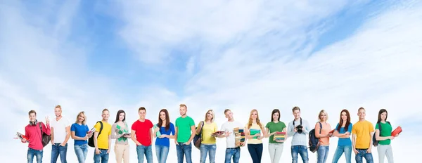 Eine große Gruppe von Schülern oder Studenten vor dem Hintergrund des Himmels. Junge Leute stehen vor der Kamera und lächeln. Bildungs- und Freundschaftskonzept. — Stockfoto