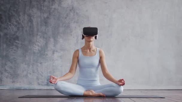 Jong en sportief meisje in sportkleding doet yoga oefeningen met behulp van virtual reality helm. Fit en slanke blonde vrouw gaat in voor sport en fitness. Gezondheidszorg, vetverbranding en. — Stockvideo