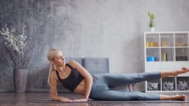 Spor giyimli genç ve sportif kız iç mekanda egzersiz yapıyor. Formda ve narin sarışın kadın spor ve spor için geliyor. Sağlık sigortası, yağ yakma ve sağlık..