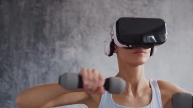 Spor giyimli genç ve sportif kız sanal gerçeklik kaskı kullanarak evde egzersiz yapıyor. Formda ve narin sarışın kadın spor ve spor için geliyor. Sağlık sigortası, yağ yakma ve sağlık..