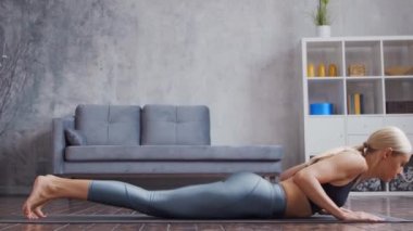 Spor giyimli genç ve sportif kız ev içinde yoga egzersizleri yapıyor. Formda ve narin sarışın kadın spor ve spor için geliyor. Sağlık sigortası, yağ yakma ve sağlık..