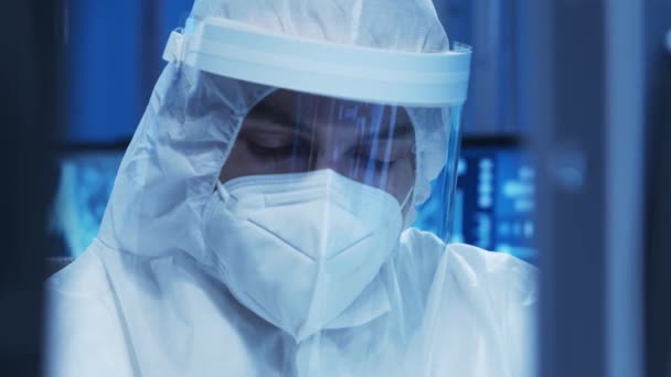 身穿防护服的医生正在一个现代化的实验室里进行科学实验和疫苗研发。实验室助理工作。科学和医学的概念. — 图库视频影像