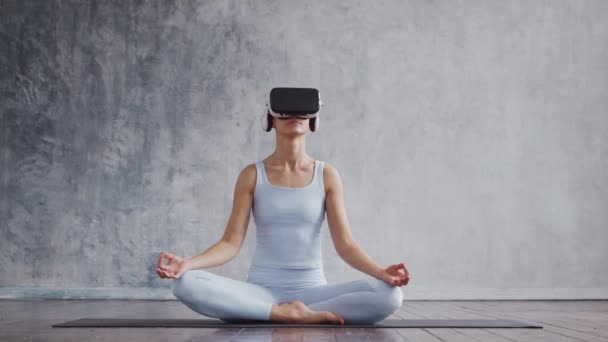 Giovane e sportiva ragazza in abbigliamento sportivo sta facendo esercizi di yoga utilizzando il casco realtà virtuale. In forma e snella donna bionda entra per lo sport e il fitness. Sanità, bruciare i grassi e. — Video Stock