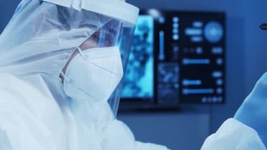 Koruyucu kıyafetli doktor modern bir laboratuvarda bilimsel deneyler yapıyor ve aşı geliştiriyor. Laboratuvar asistanı iş yerinde. Bilim ve tıp kavramı.