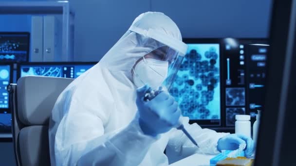身穿防护服的医生正在一个现代化的实验室里进行科学实验和疫苗研发。实验室助理工作。科学和医学的概念. — 图库视频影像