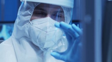 Koruyucu kıyafetli doktor modern bir laboratuvarda bilimsel deneyler yapıyor ve aşı geliştiriyor. Laboratuvar asistanı iş yerinde. Bilim ve tıp kavramı.