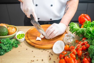 Genç aşçı modern bir mutfakta ahtapot kesiyor. Adam evde yemek hazırlıyor. Sağlıklı ve lezzetli yemekler pişirmek..