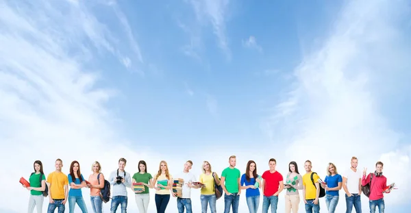 Μια μεγάλη ομάδα μαθητών ή μαθητών στο φόντο του ουρανού. Οι νέοι στέκονται μπροστά στην κάμερα και χαμογελούν. Εκπαίδευση και φιλία. — Φωτογραφία Αρχείου