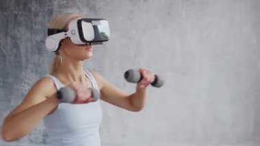 Spor giyimli genç ve sportif kız sanal gerçeklik kaskı kullanarak evde egzersiz yapıyor. Formda ve narin sarışın kadın spor ve spor için geliyor. Sağlık sigortası, yağ yakma ve sağlık..