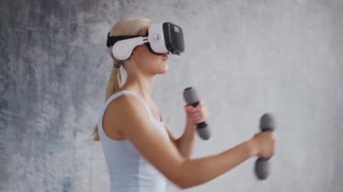 Spor giyimli genç ve sportif kız sanal gerçeklik kaskı kullanarak evde egzersiz yapıyor. Formda ve narin sarışın kadın spor ve spor için geliyor. Sağlık sigortası, yağ yakma ve sağlık..