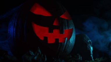 Korkunç, gülen bir balkabağı ve karanlık bir arka planda eski bir kafatası. Cadılar Bayramı, büyücülük ve sihir.