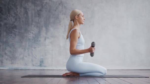 Jong en sportief meisje in sportkleding doet oefeningen in het interieur. Fit en slanke blonde vrouw gaat in voor sport en fitness. Gezondheidszorg, vetverbranding en welzijn. — Stockvideo