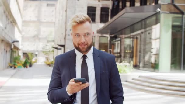 Selbstbewusster Geschäftsmann vor einem modernen Bürogebäude. Finanzinvestor geht ins Freie. Banken und Unternehmen. — Stockvideo