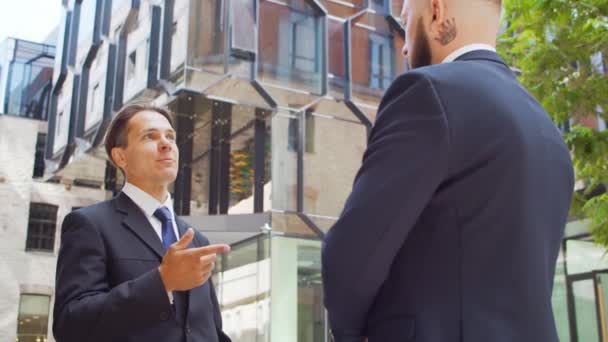 Confident businessman and his colleague in front of modern office building. Financial investors are talking outdoor. Banking and business. — Stock Video