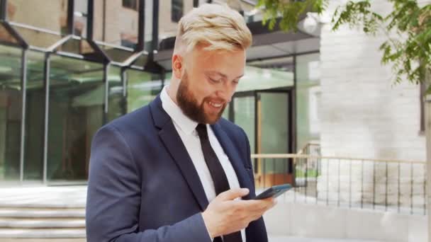 Selbstbewusster Geschäftsmann vor einem modernen Bürogebäude. Finanzinvestor geht ins Freie. Banken und Unternehmen. — Stockvideo