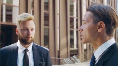 Modern ofis binasının önünde kendinden emin bir iş adamı ve meslektaşı. Finansal yatırımcılar dışarıda konuşuyorlar. Bankacılık ve iş.