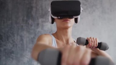 Spor giyimli genç ve sportif kız sanal gerçeklik kaskı kullanarak evde egzersiz yapıyor. Formda ve narin sarışın kadın spor ve spor için geliyor. Sağlık sigortası, yağ yakma ve sağlık..