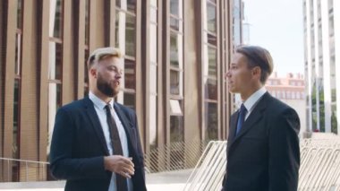 Modern ofis binasının önünde kendinden emin bir iş adamı ve meslektaşı. Finansal yatırımcılar dışarıda konuşuyorlar. Bankacılık ve iş.